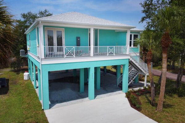 WinWay Homes Elevated Coastal Home with Aqua Siding, Upper Porch, White Railings & Open Ground-Level Carport