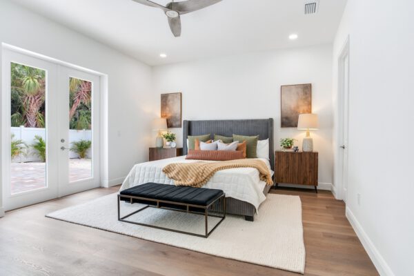 WinWay Homes Primary Bedroom in Soothing White with Neutral Bedding, French Doors to Patio, Ceiling Fan & Light Wood-Look Flooring