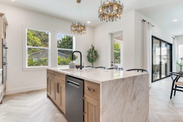 WinWay Homes Kitchen with Marble Island, Two Chandeliers, Large Windows & Warm Wood Cabinetry