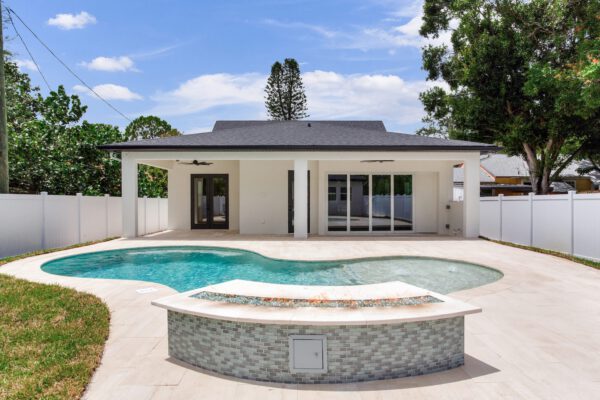 WinWay Homes Rear Exterior with Freeform Pool, Covered Lanai, White Modern Exterior & Spacious Backyard Patio