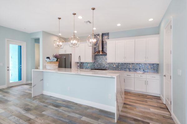WinWay Homes Kitchen with Pale Blue Walls, White Cabinetry, Decorative Backsplash & Stainless Appliances