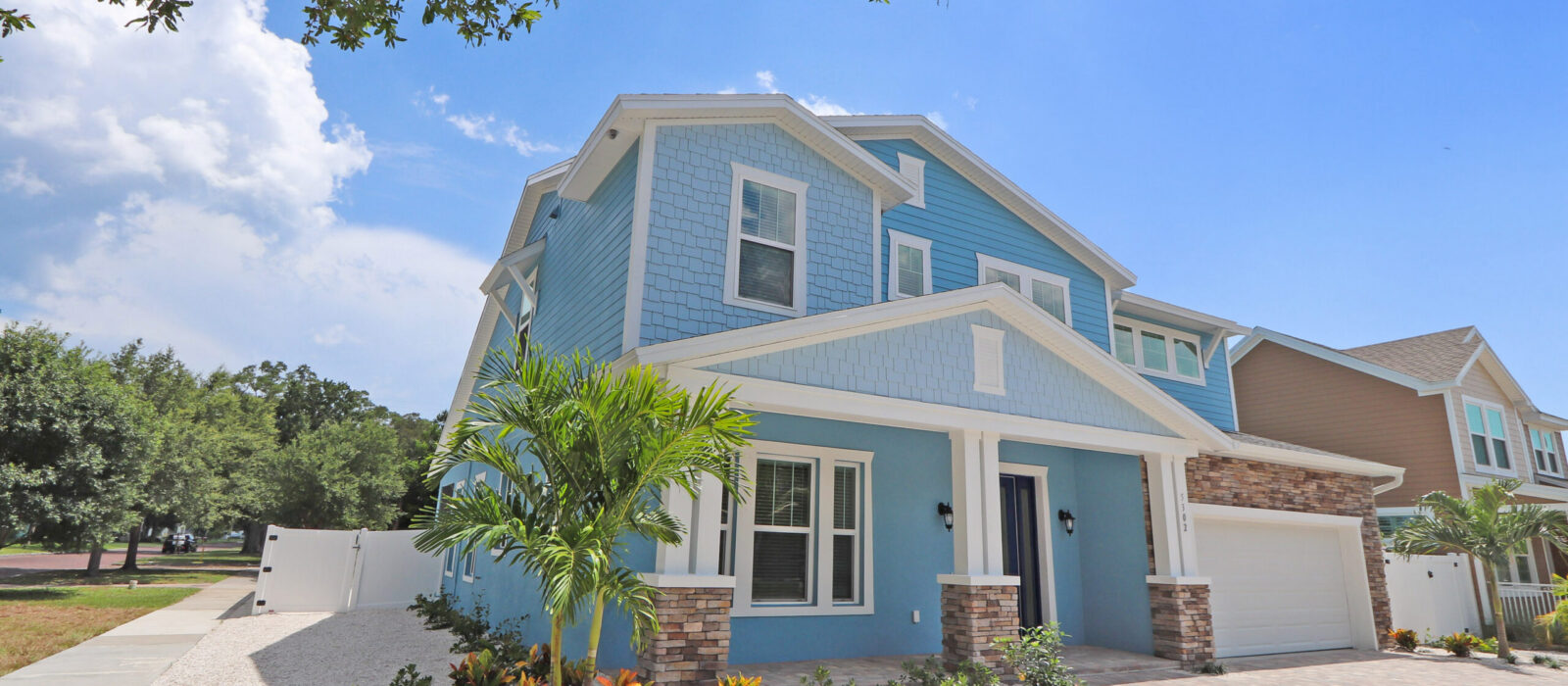 New WinWay Custom Home with 2 Stories, Blue Siding and White Trim, Stone Details, and New Landscaping with Palm Tree
