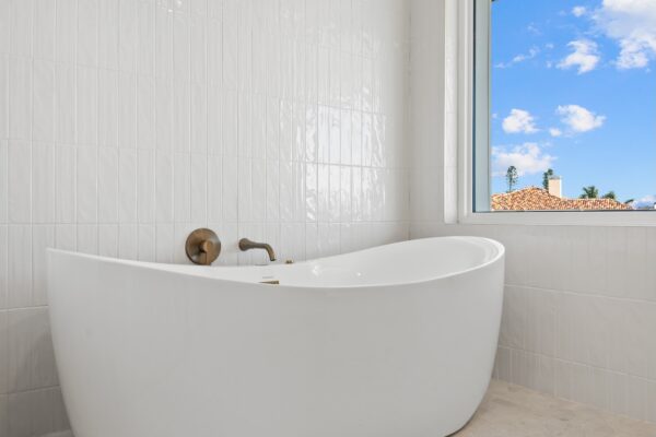 WinWay Homes Spa-Style Bathroom with Freestanding White Garden Tub, White Tile Wall, and Picturesque Window
