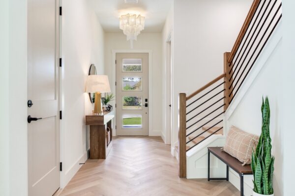 WinWay Homes Front Hallway with Staircase, Glass Door, Herringbone Flooring, Wood Handrail & White Walls