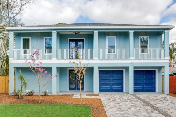 WinWay Homes Exterior in Aqua and Navy Accents with Columns, White Railing, and Two Garage Doors