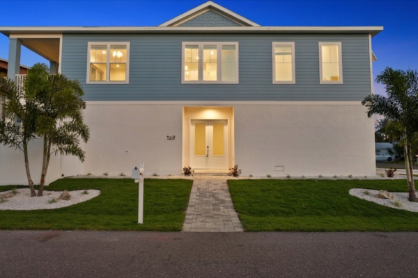 WinWay Homes Costal Home Exterior in Light Gray Siding, White Stucco, and French Doors at Dusk with Lighting