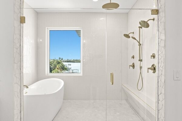 WinWay Homes Spa Bathroom with Arched Opening, Freestanding Tub, Dual Shower Heads, Gold Fixtures, Light Tile Flooring & Water View Window