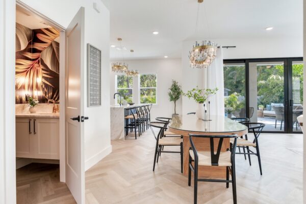 WinWay Homes Dining Area with Round Table, Open Kitchen View, Sliding Glass Doors, Herringbone Flooring & Modern Chandelier