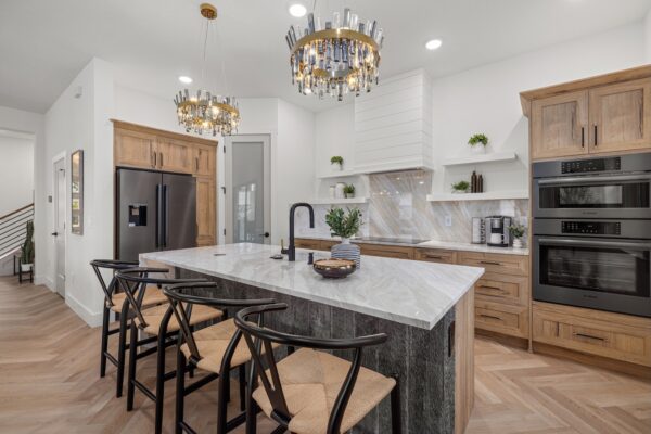 WinWay Homes Kitchen with Marble Island, Wood Cabinetry, Statement Chandeliers, Double Wall Ovens & Herringbone Flooring