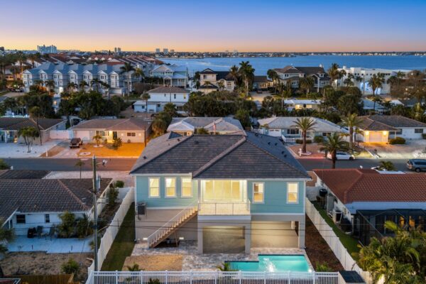 WinWay Homes Elevated Coastal Home Aerial with Pool, Water View, Aqua Siding & Raised Main Living Level