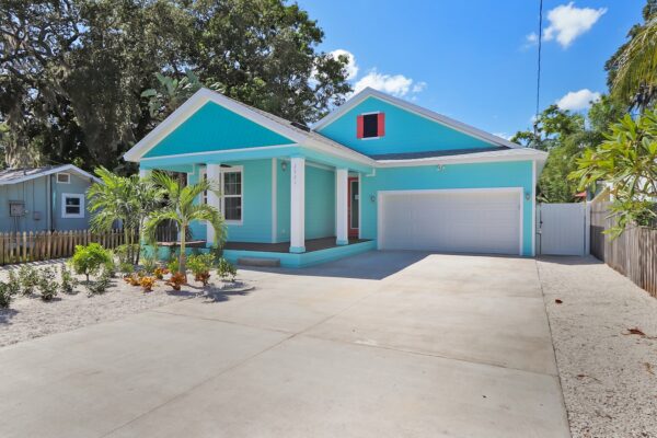 WinWay Homes 1-Story Coastal Cottage with Turquoise Siding, Coral Dormer Accent, Covered Porch, Attached Garage & Wide Concrete Driveway