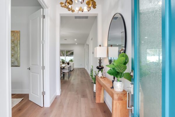 WinWay Homes Front Entry Hall with Teal Front Door, Console Table, light wood-look flooring, statement chandelier & open-concept view