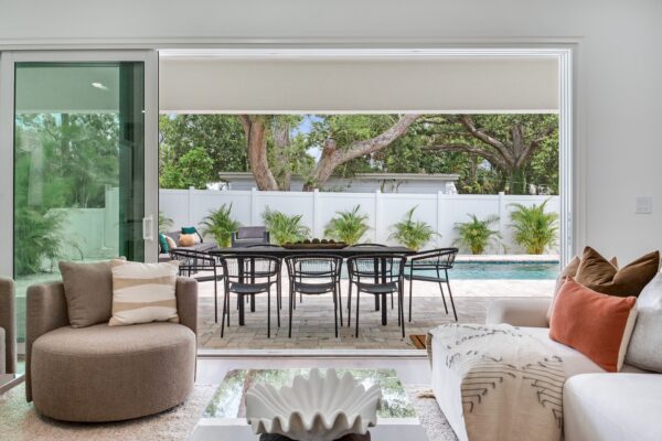 WinWay Homes Living Room with large opening to covered patio, outdoor dining area, pool view & bright indoor-outdoor design