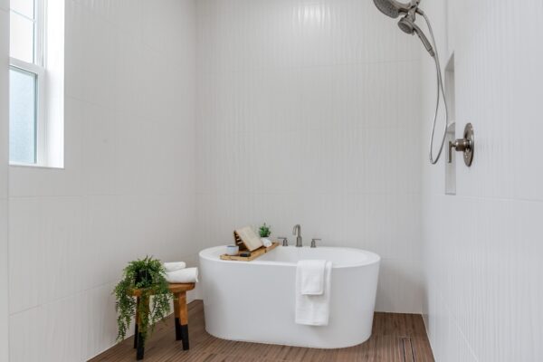 WinWay Homes Spa Bathroom with Freestanding Tub, Shower Fixture, Wood-Look Flooring, White Walls & Window Light