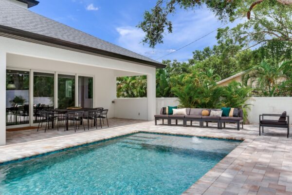 WinWay Homes Backyard Pool with Paver Deck, Covered Patio, Outdoor Lounge Area & Modern White Exterior