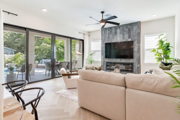 WinWay Homes Contemporary Living Room with Sliding Glass Doors, Fireplace Wall, Light Flooring, Ceiling Fan & Open Indoor-Outdoor View