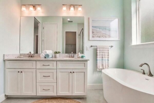 Pale Green Bathroom with Freestanding Tub, Marble-Topped White, Double Vanity and Sconce Lighting