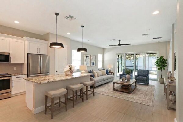 WinWay Homes Open Kitchen and Living Area with Bar Seating, Sliding Glass Doors, Tile Flooring & Neutral Furnishings