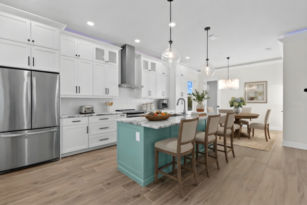 WinWay Homes Kitchen with Aqua Island, White Cabinetry, Adjacent Dining Area & Light Wood-Look Flooring