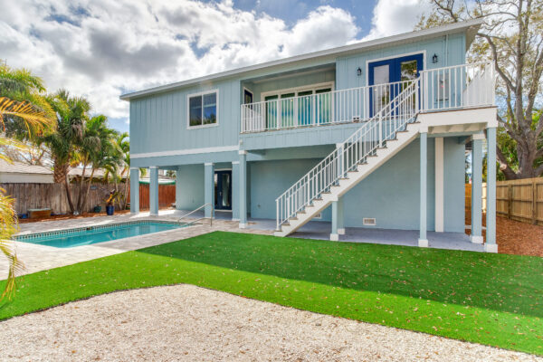 2-Story Elevated Home in Aqua with White Railing, Stairs, and Geometric Pool
