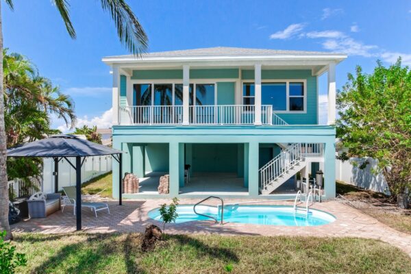 WinWay Homes Elevated Coastal Home With Pool, Upper Balcony, White Staircase, Aqua Siding & Backyard Patio
