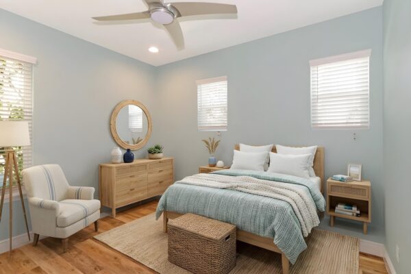 WinWay Homes Bedroom with light blue walls, white ceiling fan, wood-look flooring, upholstered bed & coastal-style furnishings