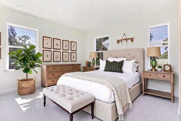 WinWay Homes Primary Bedroom with Pale Yellow Walls, Three Windows, Upholstered Bed & Light Flooring