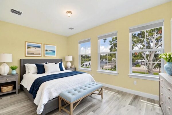 WinWay Homes Primary Bedroom with Yellow Walls, Three Windows, Upholstered Bed & Light Flooring