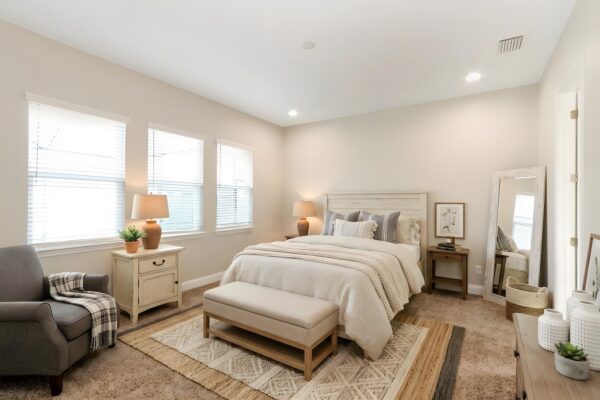 WinWay Homes Primary Bedroom with Neutral Palette, Three Windows, Upholstered Bed & Carpet Flooring