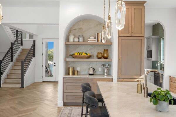 WinWay Homes Open Kitchen in Neutral Tones with Coffee Bar, Island, Crystal Pendant Lighting and View of Stairway and Home Entry