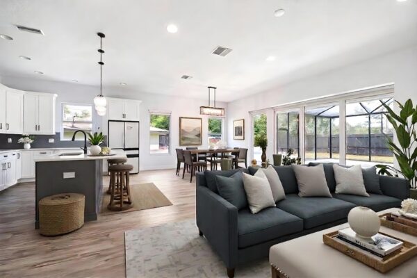 WinWay Homes Open Dining And Living Area With Screened Patio View, Wood-Look Flooring, Dark Sofa, Dining Table & White Kitchen