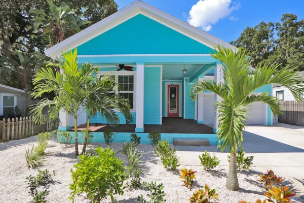 WinWay Homes 1-Story Coastal Cottage with Turquoise Siding, Coral Front Door, Covered Porch, Tropical Landscaping & Driveway