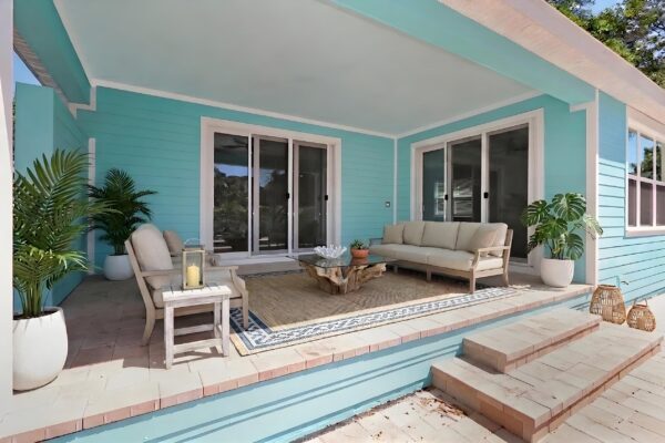 WinWay Homes Covered Outdoor Living Area with Aqua Siding, lounge seating, sliding glass doors, wood-look deck steps & coastal patio styling