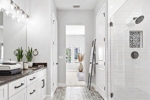 WinWay Homes Spa Bathroom With Patterned Tile Flooring, White Double Vanity, Glass Shower, Black Fixtures & Bright Modern Finishes