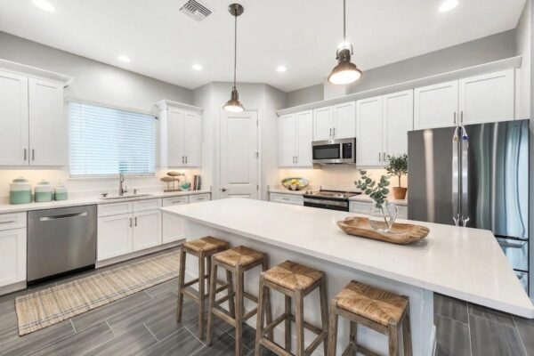 WinWay Homes Kitchen with Oversized Peninsula, Bar Stools, White Cabinetry, Pendant Lights & Gray Tile Flooring
