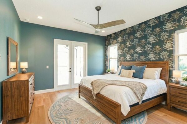 WinWay Homes Primary Bedroom With Teal Accent Walls, Botanical Wallpaper, Wood Flooring, White Double Doors & Warm Wood Furnishings