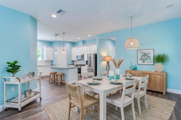 WinWay Homes Dining and Living Area with Aqua Walls, Open Kitchen, Light Flooring & Coastal Furnishings