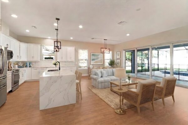 WinWay Homes Open Kitchen and Living Area with Waterfall Island, Sliding Glass Doors, Neutral Furnishings & Light Flooring