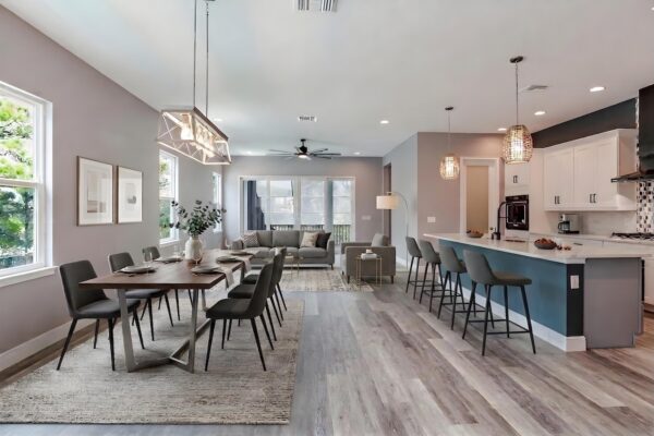 WinWay Homes Open Dining and Kitchen Area with Modern Chandelier, Teal Island, Bar Seating, Wide-Plank Flooring & Open Living Room View